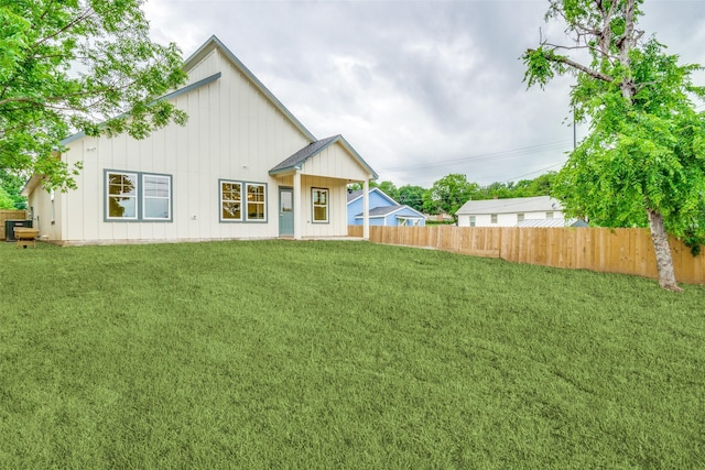 back of property featuring a lawn, fence, and board and batten siding