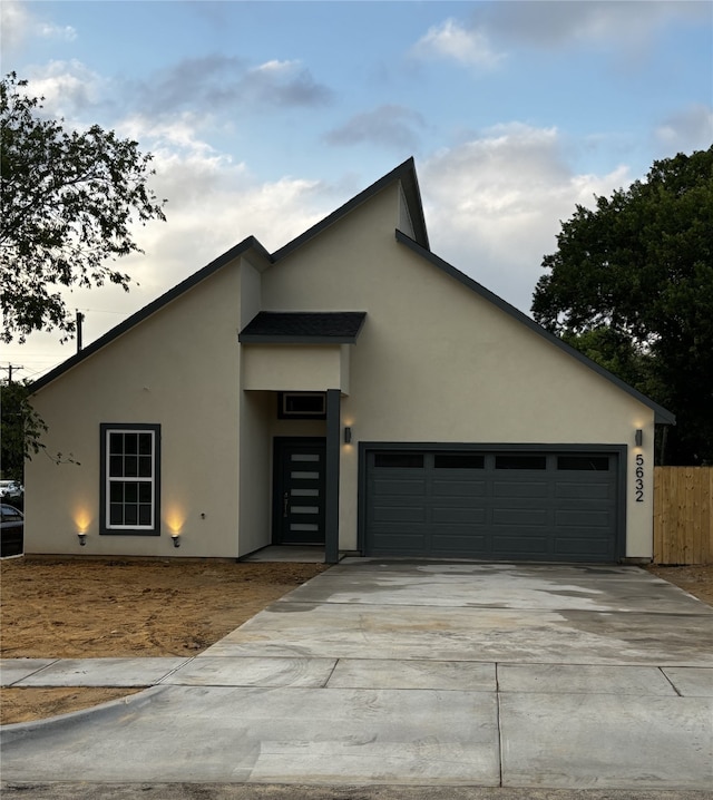 view of front of home featuring concrete driveway, a garage, fence, and stucco siding