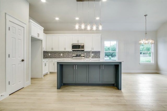 kitchen with appliances with stainless steel finishes, white cabinets, and tasteful backsplash