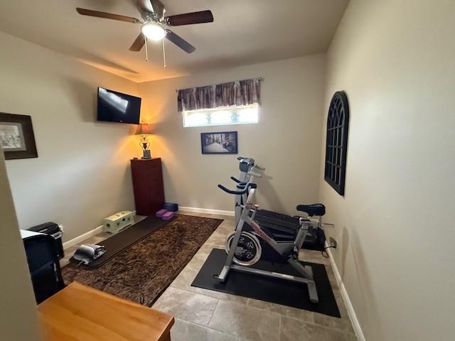 workout room featuring baseboards and ceiling fan