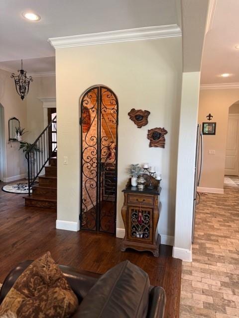 entryway with arched walkways, stairway, baseboards, ornamental molding, and recessed lighting