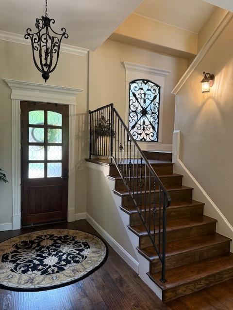 entrance foyer with stairway, baseboards, dark wood finished floors, and a chandelier