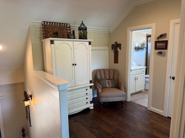sitting room with dark wood finished floors, ornamental molding, and lofted ceiling