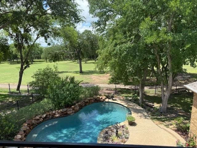 view of swimming pool with fence and a lawn