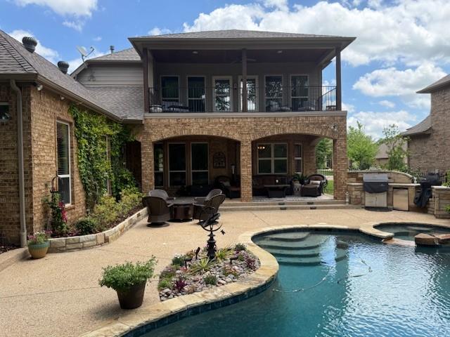 back of property featuring area for grilling, roof with shingles, a balcony, and a patio area