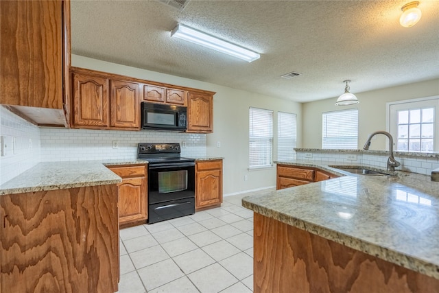 kitchen with visible vents, tasteful backsplash, brown cabinets, a sink, and black appliances