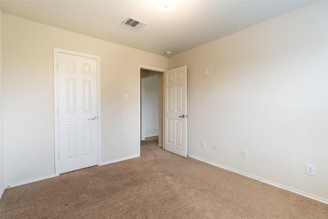 unfurnished bedroom featuring baseboards, visible vents, and light colored carpet