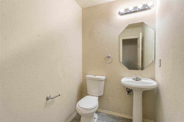 half bathroom featuring baseboards, a sink, and toilet