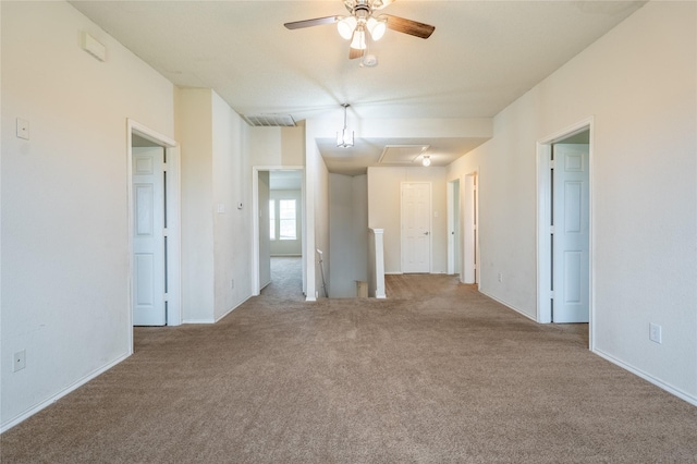 carpeted empty room featuring baseboards, attic access, and a ceiling fan