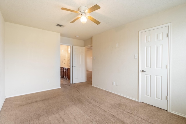 unfurnished bedroom with visible vents, carpet floors, baseboards, ceiling fan, and ensuite bath