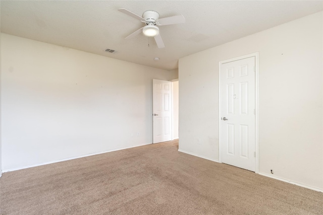 carpeted spare room featuring visible vents, baseboards, and ceiling fan