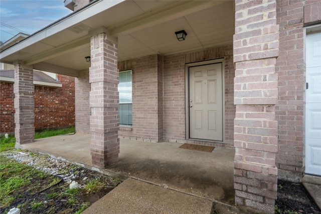property entrance featuring brick siding and covered porch