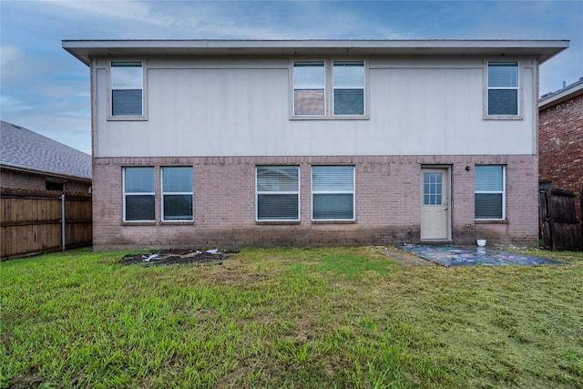 back of property with a yard, brick siding, a patio, and a fenced backyard