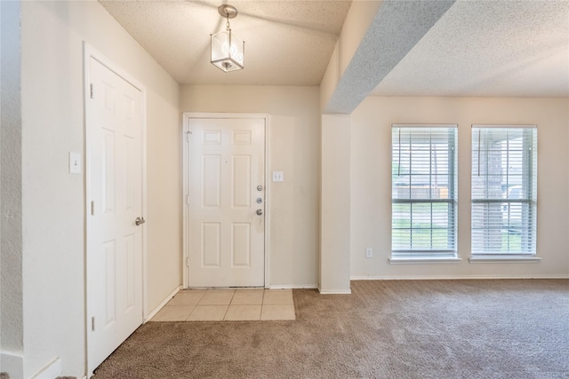 entrance foyer featuring baseboards, a textured ceiling, and light carpet