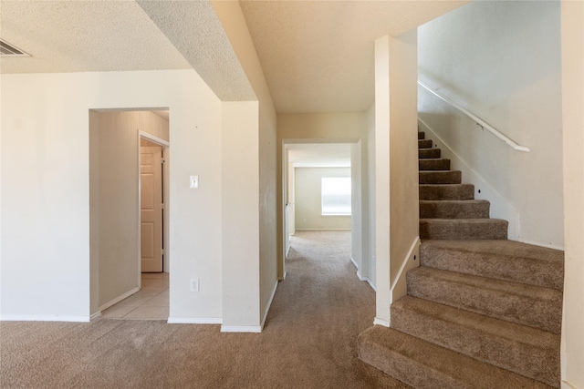 stairs with carpet floors, baseboards, and visible vents