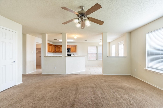 unfurnished living room featuring baseboards, a ceiling fan, a textured ceiling, and light carpet