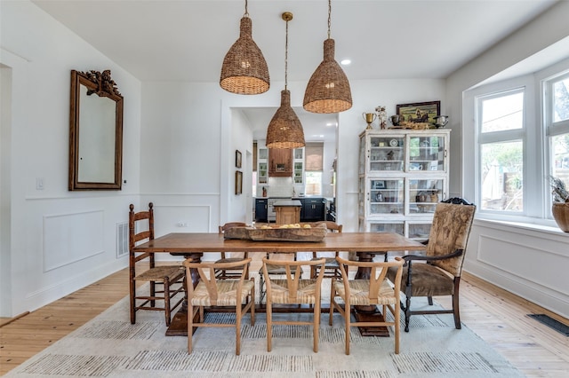 805 Howell St, Mckinney, TX 75069 - dining room with light wood finished floors, a decorative wall, and wainscoting