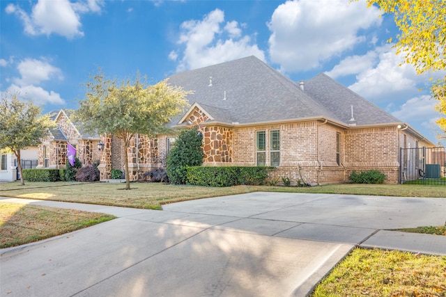 2417 Roosevelt Ave, Fort Worth, TX 76164 - ranch-style house with brick siding, a shingled roof, a front lawn, and central AC