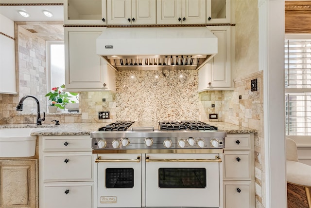 kitchen with range with two ovens, a wealth of natural light, a sink, and range hood
