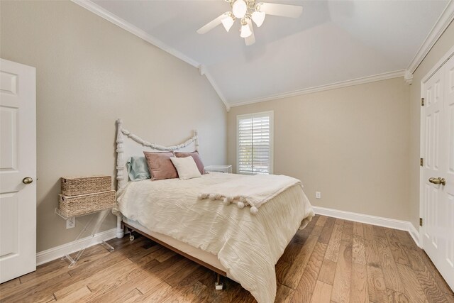 bedroom featuring crown molding, baseboards, lofted ceiling, and wood finished floors
