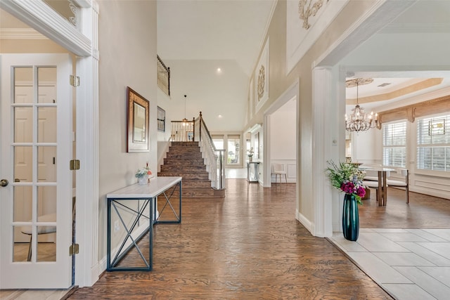 foyer with stairs, a chandelier, plenty of natural light, and wood finished floors