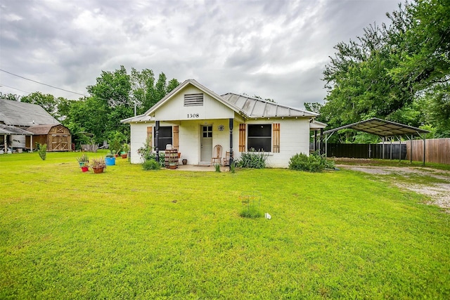 bungalow featuring a front lawn, a detached carport, fence, concrete block siding, and a porch