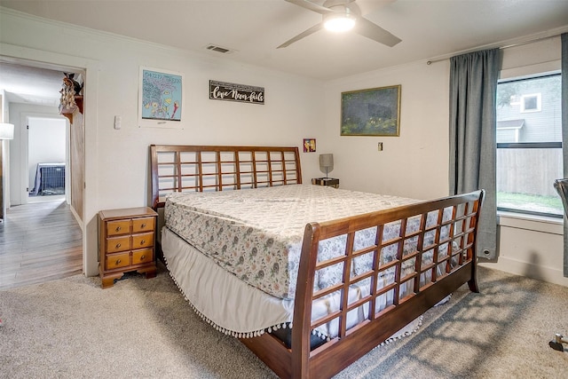 bedroom with carpet floors, visible vents, and ornamental molding