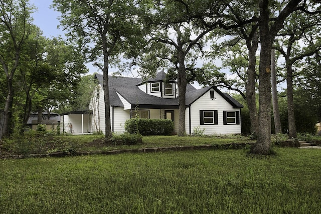 view of front of home with a shingled roof and a front lawn