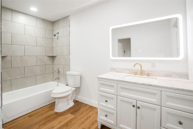 bathroom featuring wood finished floors, shower / washtub combination, vanity, baseboards, and toilet