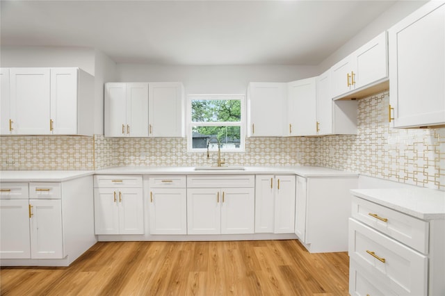 kitchen featuring light wood-type flooring, a sink, white cabinetry, and light countertops
