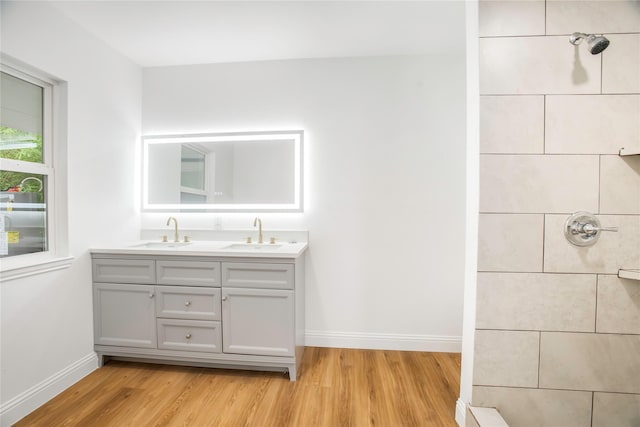 full bath with baseboards, a sink, and wood finished floors