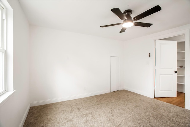 carpeted empty room with baseboards and a ceiling fan