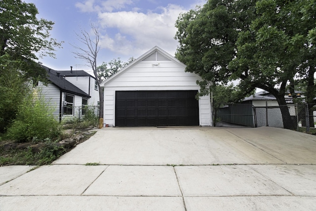 garage with fence and concrete driveway