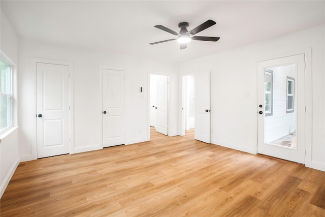 unfurnished bedroom with baseboards, a ceiling fan, multiple closets, and light wood-style flooring