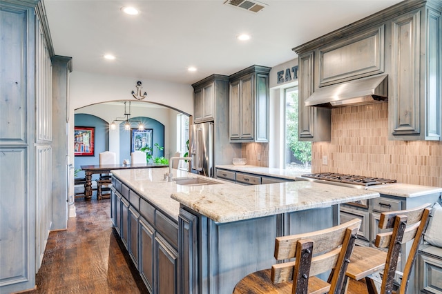 kitchen with visible vents, ventilation hood, tasteful backsplash, arched walkways, and stainless steel appliances