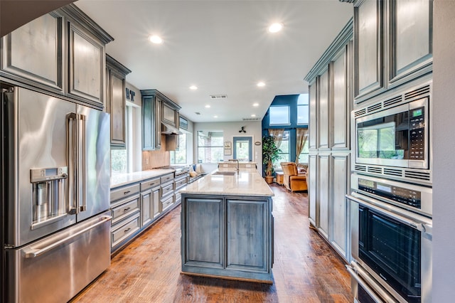 kitchen featuring light stone countertops, appliances with stainless steel finishes, a center island with sink, and a wealth of natural light