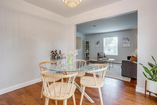 dining area with baseboards, wood finished floors, and visible vents