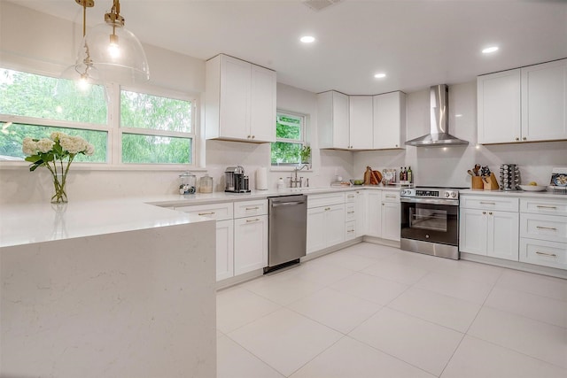 kitchen featuring a sink, white cabinets, stainless steel appliances, recessed lighting, and wall chimney exhaust hood