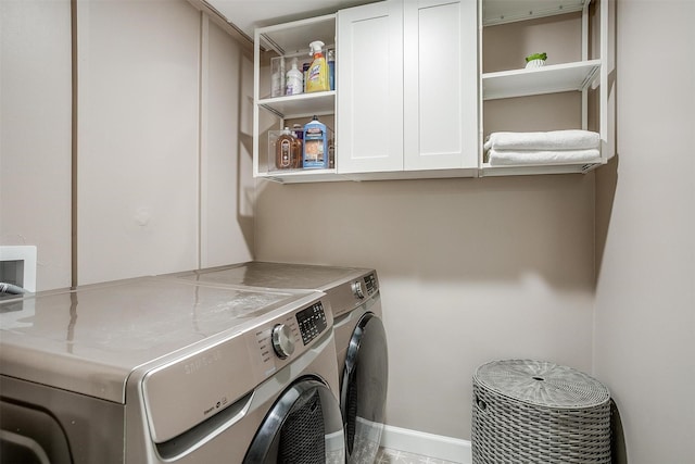 laundry area with cabinet space, separate washer and dryer, and baseboards