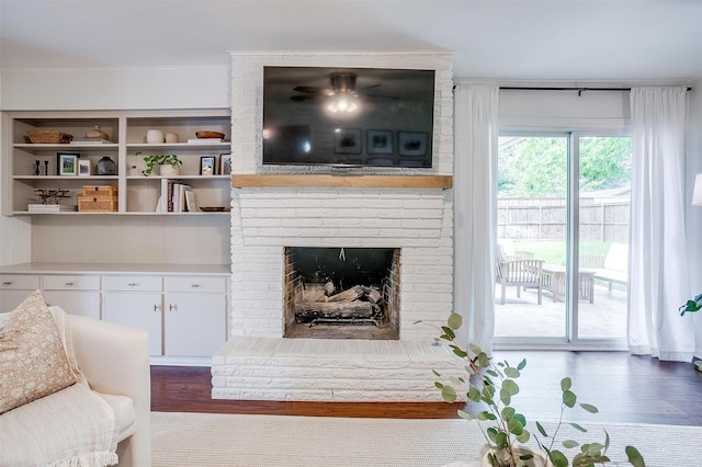 living room with a brick fireplace and wood finished floors