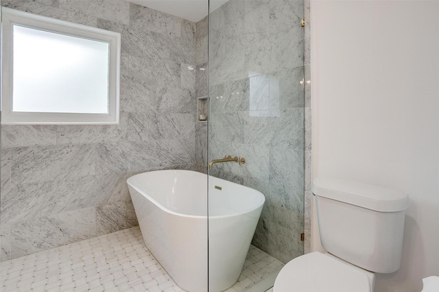 bathroom featuring a freestanding tub, toilet, and tile walls