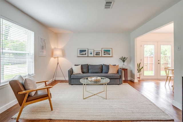 living area with visible vents, baseboards, wood finished floors, and a wealth of natural light