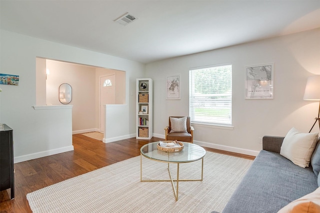 living room featuring visible vents, baseboards, and wood finished floors