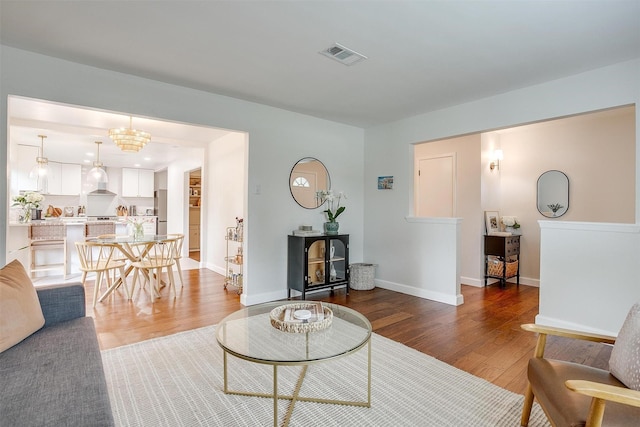 living area with baseboards, visible vents, and wood finished floors