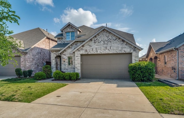 french country style house with driveway, a garage, brick siding, a front lawn, and a shingled roof