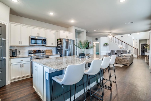 kitchen featuring visible vents, open floor plan, dark wood-style floors, white cabinets, and stainless steel appliances