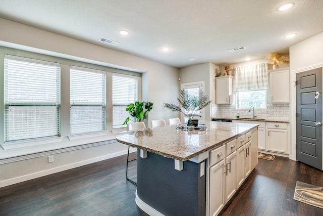 kitchen featuring visible vents, a sink, white cabinetry, and a breakfast bar area