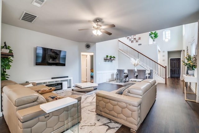 living room with ceiling fan, visible vents, wood finished floors, and stairway