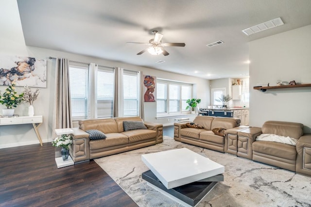 living area with dark wood-style flooring, ceiling fan, visible vents, and baseboards