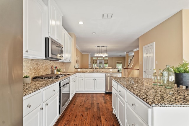 kitchen with visible vents, a peninsula, white cabinets, and stainless steel appliances